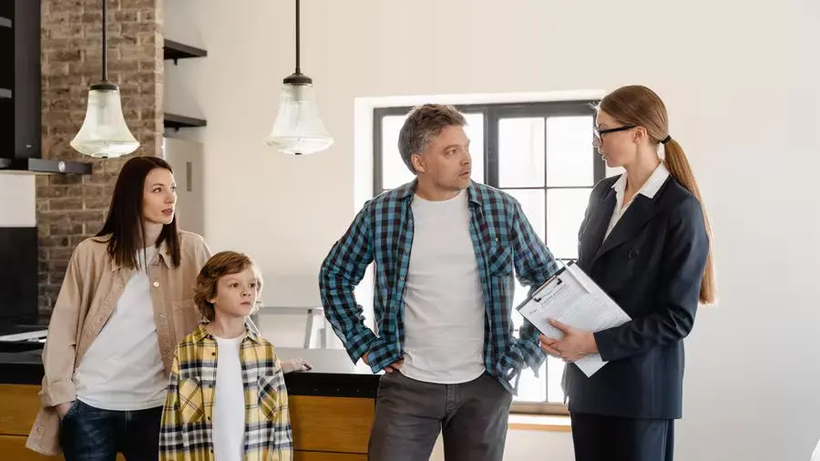 Family with child talks to real estate agent in modern kitchen during home showing.