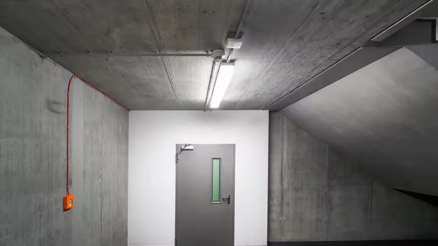 Stark and minimalist basement featuring a gray emergency door and industrial design.
